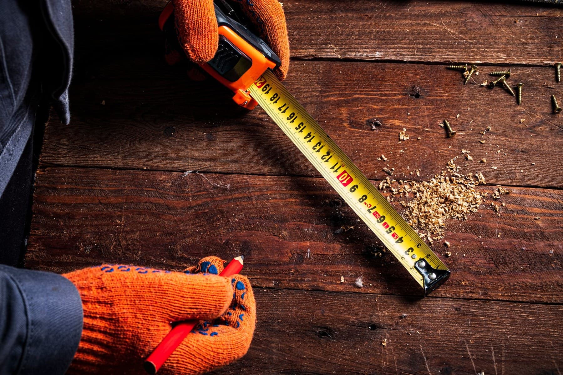 Representative carpenter measuring lumber during layout and structural preparation