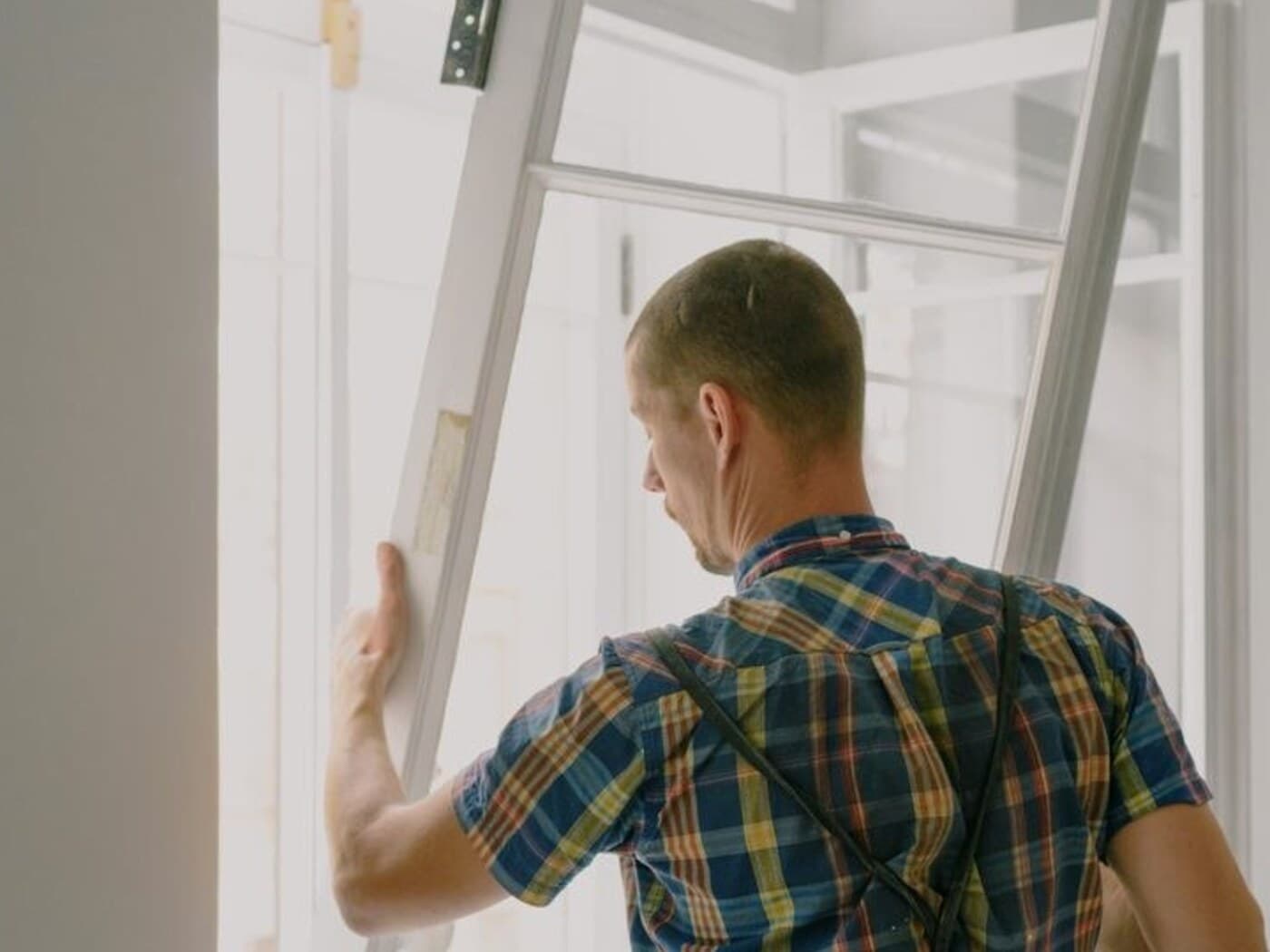 Representative installer positioning a replacement window at a residential opening
